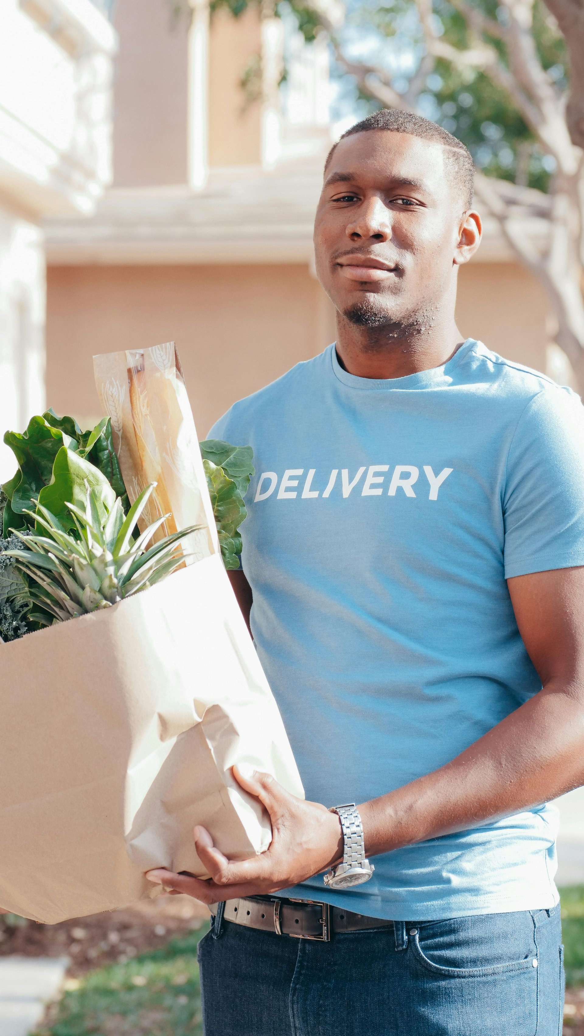A Grocery List Plus delivery driver smiling, holding a bag of fresh groceries
